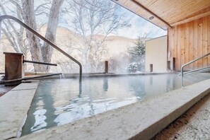 A hot spring area with a wooden interior, a concrete pool, and a view of trees and hills. - Shigakogen Milky Hot Spring Keikokunoyu (Yamanouchi)