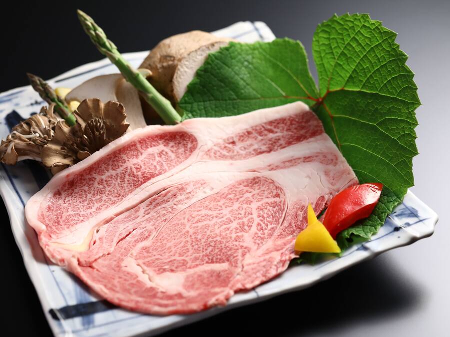 A plate with raw meat, mushrooms, and vegetables.