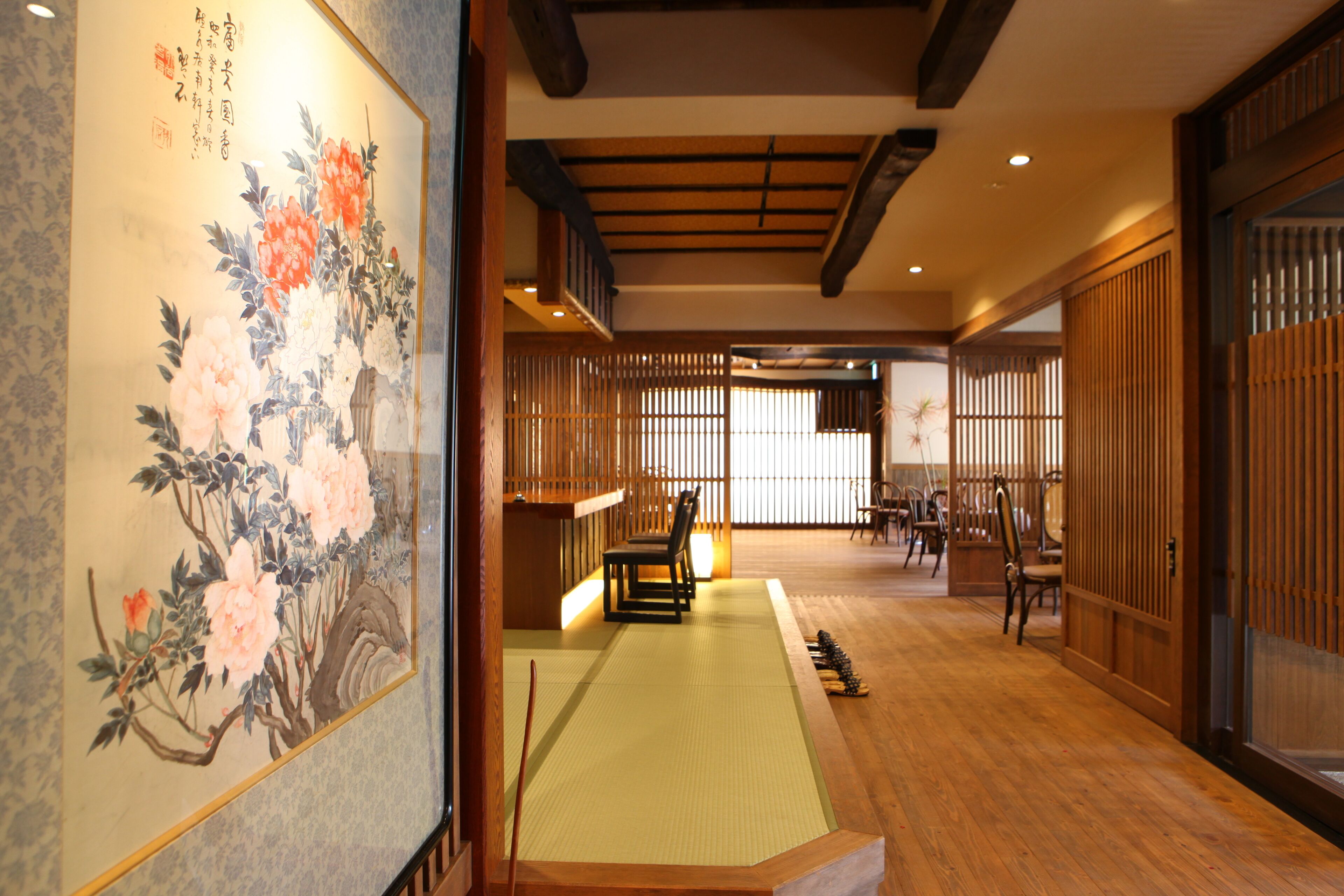 A traditional Japanese room with tatami flooring, a shoji screen, and a calligraphy painting.