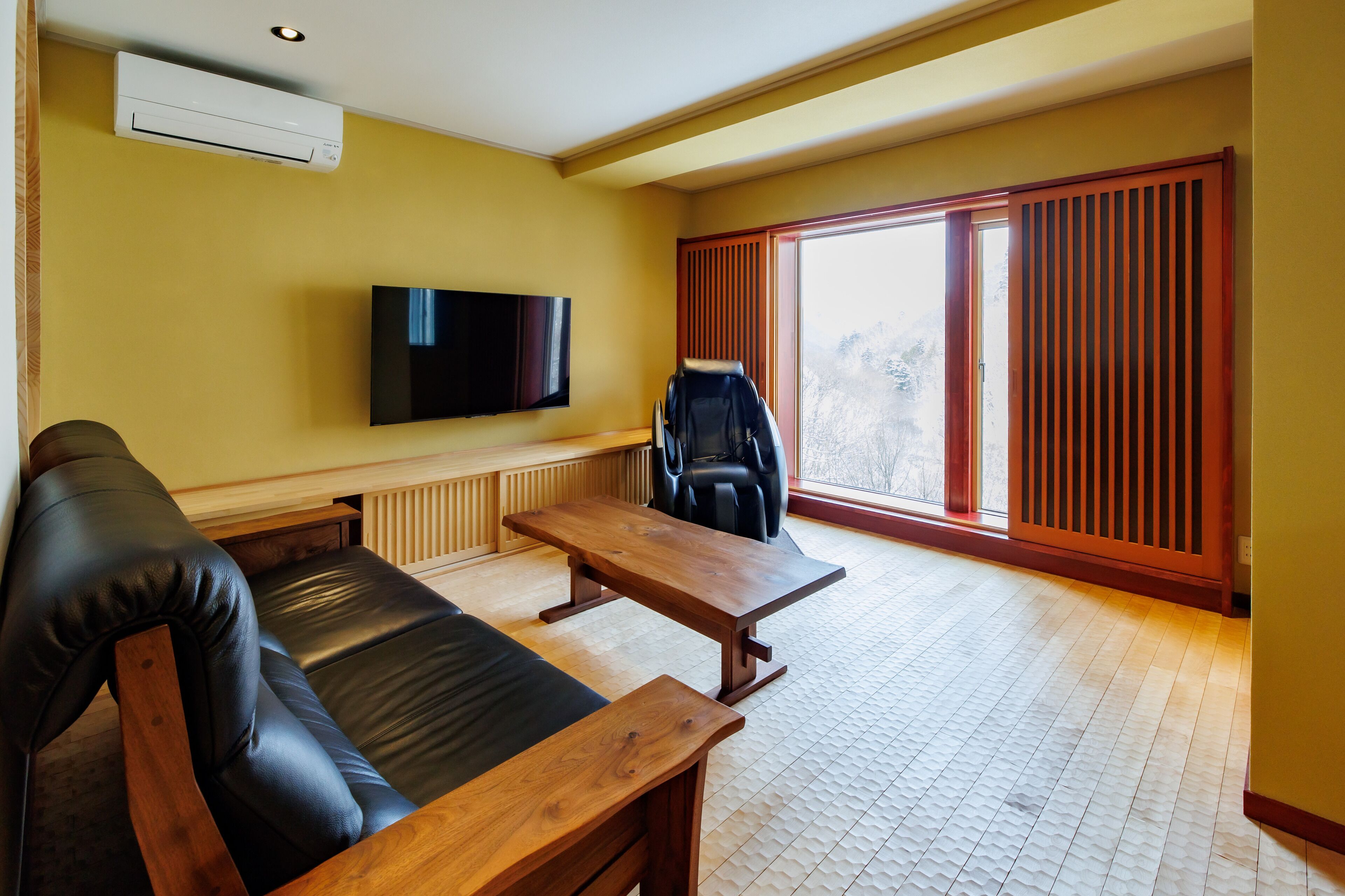 A living room with a sofa, a wooden coffee table, a television, and a sliding door leading to a balcony.