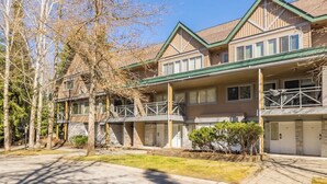 A multi-story building with a balcony, a garage, and a well-maintained lawn. - Walkable everywhere with free parking and shared hot tub (Whistler)