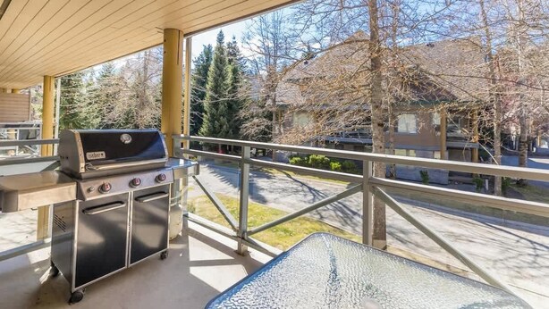 A covered outdoor area with a grill, a table, and a view of a residential street. - Walkable everywhere with free parking and shared hot tub (Whistler)