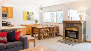 A cozy living room with a fireplace, wooden dining table, and a sofa. - Walkable everywhere with free parking and shared hot tub (Whistler)