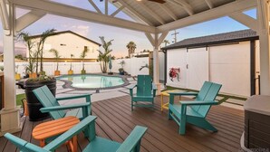 Een overdekt terras met zwembad, buitenmeubels en een garage.