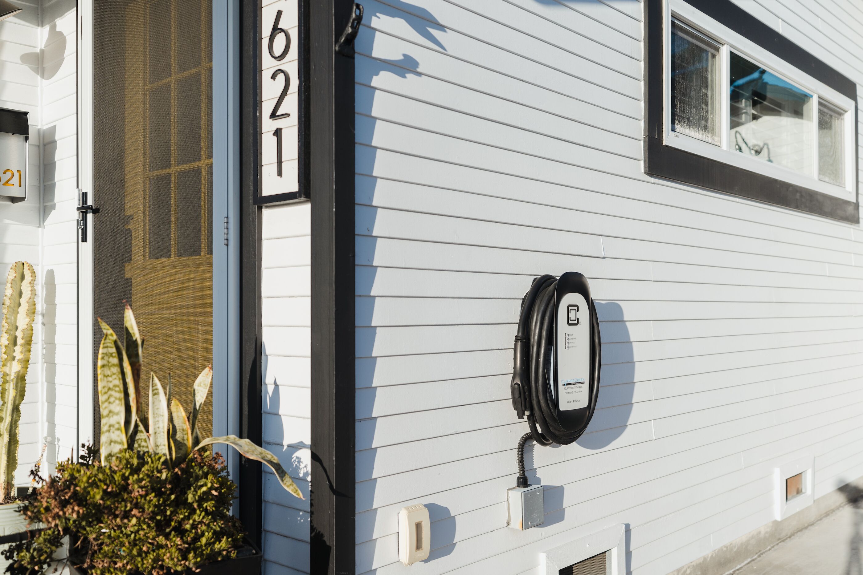 Une maison mobile blanche, avec le numéro « 621 » peint sur le côté, un téléphone noir et une petite fenêtre.