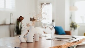 Een eettafel met twee witte vazen, een wijnglas en een bord.