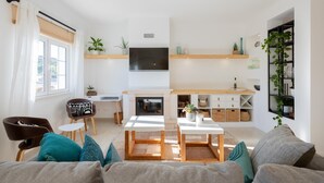 Un salon moderne doté d’une cheminée, d’un coin repas et d’un téléviseur fixé au mur.