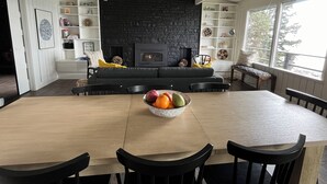 Un salon moderne avec une cheminée, une table à manger en bois et des chaises noires.