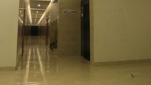 A modern hotel corridor with a "WELCOME" sign, reflective floors, and recessed lighting.