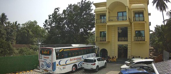 Un autobús estacionado frente a un edificio con balcón y un coche al frente.