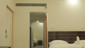 A hotel room with a large bed, a bedside table, a mirror, and a bathroom visible through an open door.