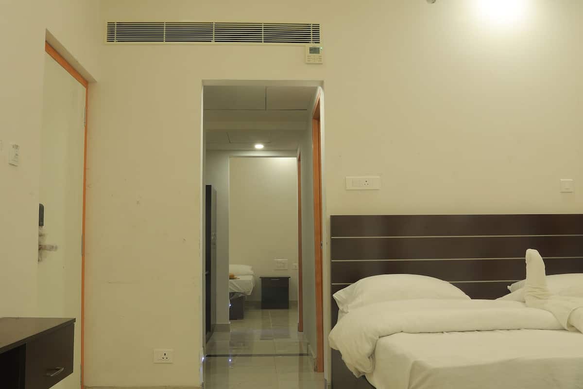 A hotel room with a large bed, a bedside table, a mirror, and a bathroom visible through an open door.