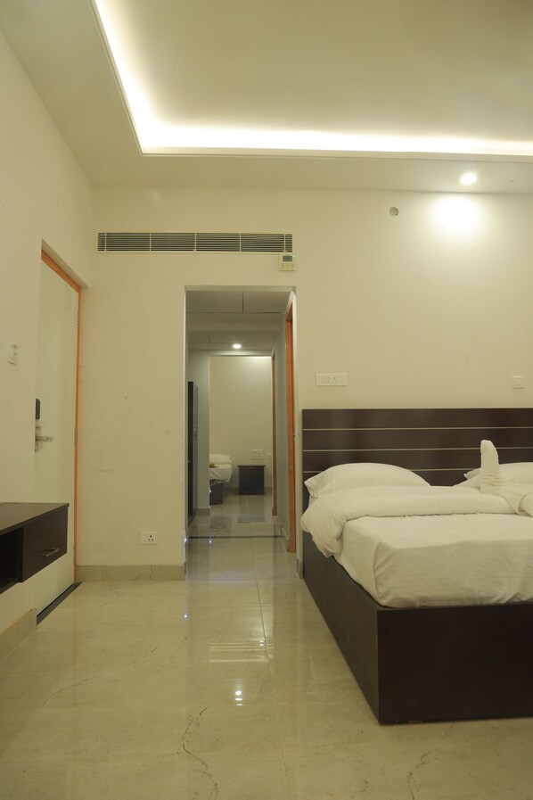 Habitación de hotel con una cama grande, una mesita de noche, un espejo y un baño visible a través de una puerta abierta.