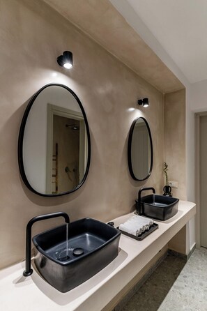 A modern bathroom with two round mirrors, a black sink, and a towel rack. - Arotron Santorini (Santorini)