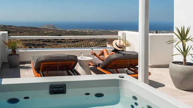 A rooftop terrace with a hot tub, lounge chairs, and potted plants. - Arotron Santorini (Santorini)