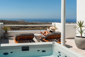 A rooftop terrace with a hot tub, lounge chairs, and potted plants. - Arotron Santorini (Santorini)