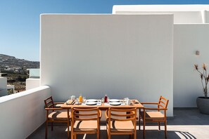 A rooftop terrace with a table set for breakfast, overlooking a hilly landscape. - Arotron Santorini (Santorini)