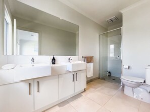 A modern bathroom with a large mirror, two sinks, a toilet, and a glass shower enclosure. - Stylish Berwick Home with WiFi, Smart TV, Garage (Berwick)