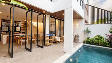 Una casa moderna con piscina, espacios abiertos para sala y comedor, y una escalera que conduce al piso superior.