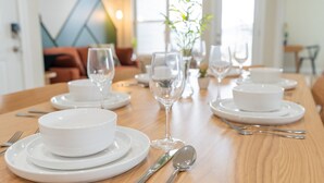 A dining table set with white plates, bowls, and cutlery, with a vase of flowers in the background. - Mt View ★ King bed, Pool, Arcade, Family-friendly ★ 2mi Branson Strip! (Branson)