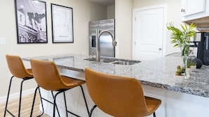 A kitchen with a granite countertop, stainless steel appliances, and three bar stools. - Mt View ★ King bed, Pool, Arcade, Family-friendly ★ 2mi Branson Strip! (Branson)