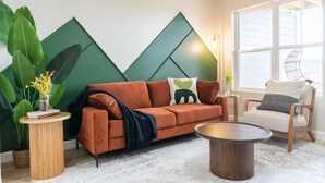 A modern living room with a sofa, a coffee table, and a chair. There is a large window providing natural light and a view of the outdoors. - Mt View ★ King bed, Pool, Arcade, Family-friendly ★ 2mi Branson Strip! (Branson)
