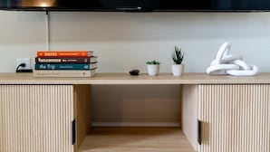 A modern, minimalist desk with a flat-screen TV, a stack of books, a small potted plant, and a white abstract sculpture. - Mt View ★ King bed, Pool, Arcade, Family-friendly ★ 2mi Branson Strip! (Branson)