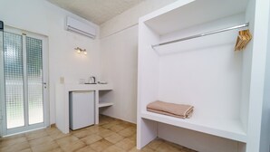 A compact room with a kitchenette, a built-in bench with a towel, and a clothing rack. - Mayo Rooms (Zakynthos)