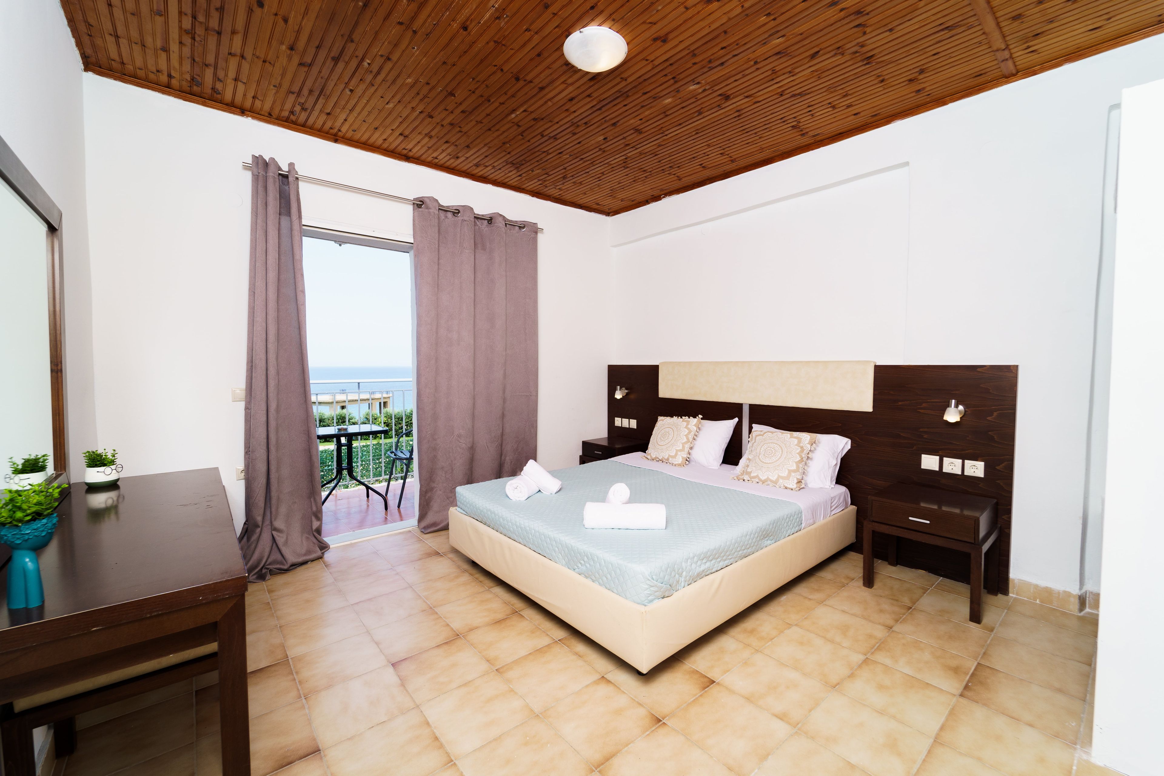 Ein Schlafzimmer mit Bett, Nachttischen, einem Schreibtisch und Blick ins Freie.
