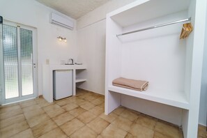 Une pièce compacte dotée d’une kitchenette, d’une banquette intégrée avec une serviette et d’un porte-vêtements.