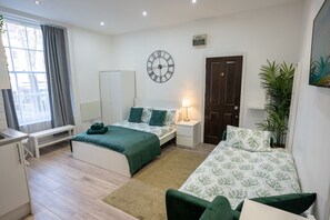 Une chambre à coucher avec un lit, une table de chevet, une lampe et une horloge au mur.