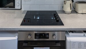 Une cuisine moderne avec des armoires blanches, une hotte de cuisinière en acier inoxydable, un four encastré, un four à micro-ondes et un grille-pain.