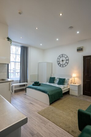 Un dormitorio moderno con cama, mesita de noche y un reloj de pared.