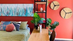 Una habitación con cama, una mesa de madera, una estantería y dos cestas fijadas a la pared.