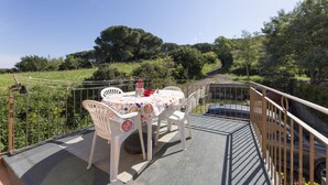 An outdoor dining area with a table and chairs, surrounded by greenery and a clear sky. - Casetta Ginevra Country & Modern (Portoferraio)