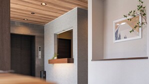 A modern interior with a wooden ceiling, recessed lighting, a dark door, and a framed picture on the wall. - HAOSTAY KAWAGUCHIKO ART MUSEUM. (Fujikawaguchiko)