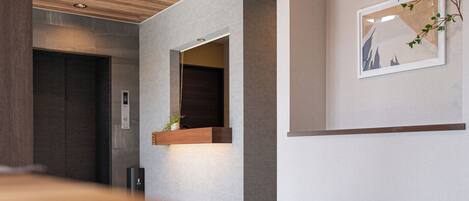 A modern interior with a wooden ceiling, recessed lighting, a dark door, and a framed picture on the wall.