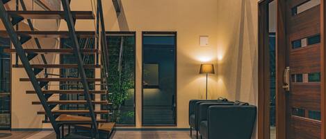 A modern interior with a staircase, a door, and a seating area.