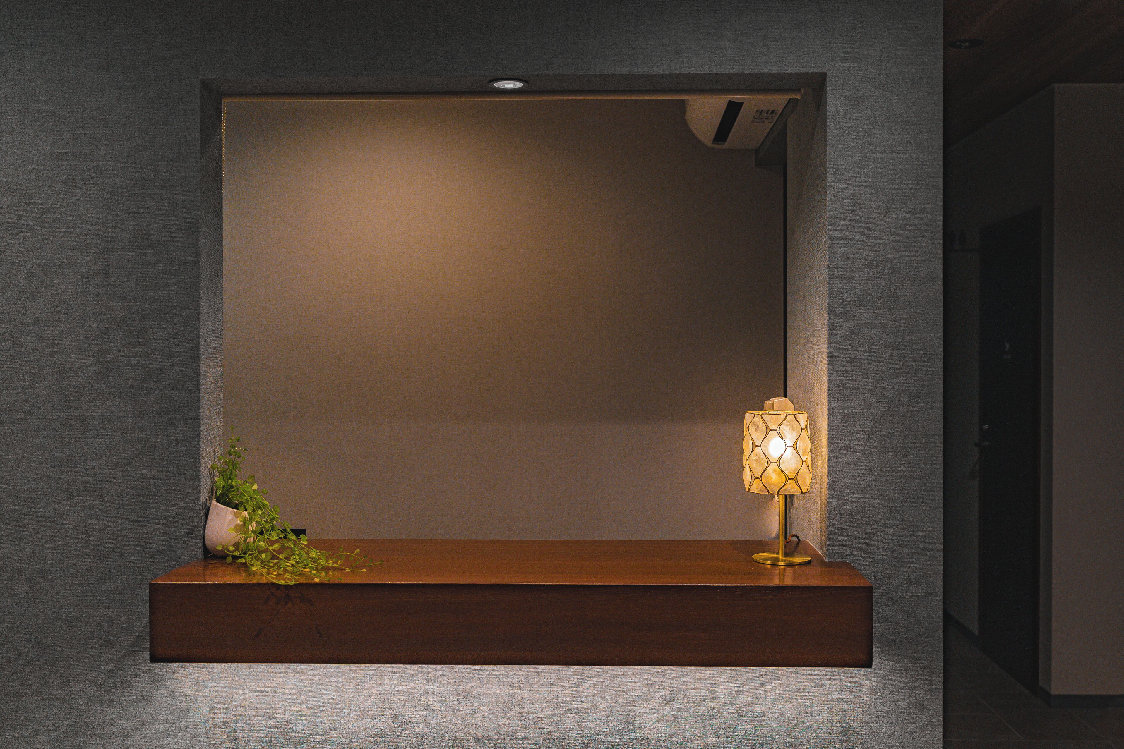 A minimalist room with a wooden console table, a wall-mounted lamp, and a small potted plant.
