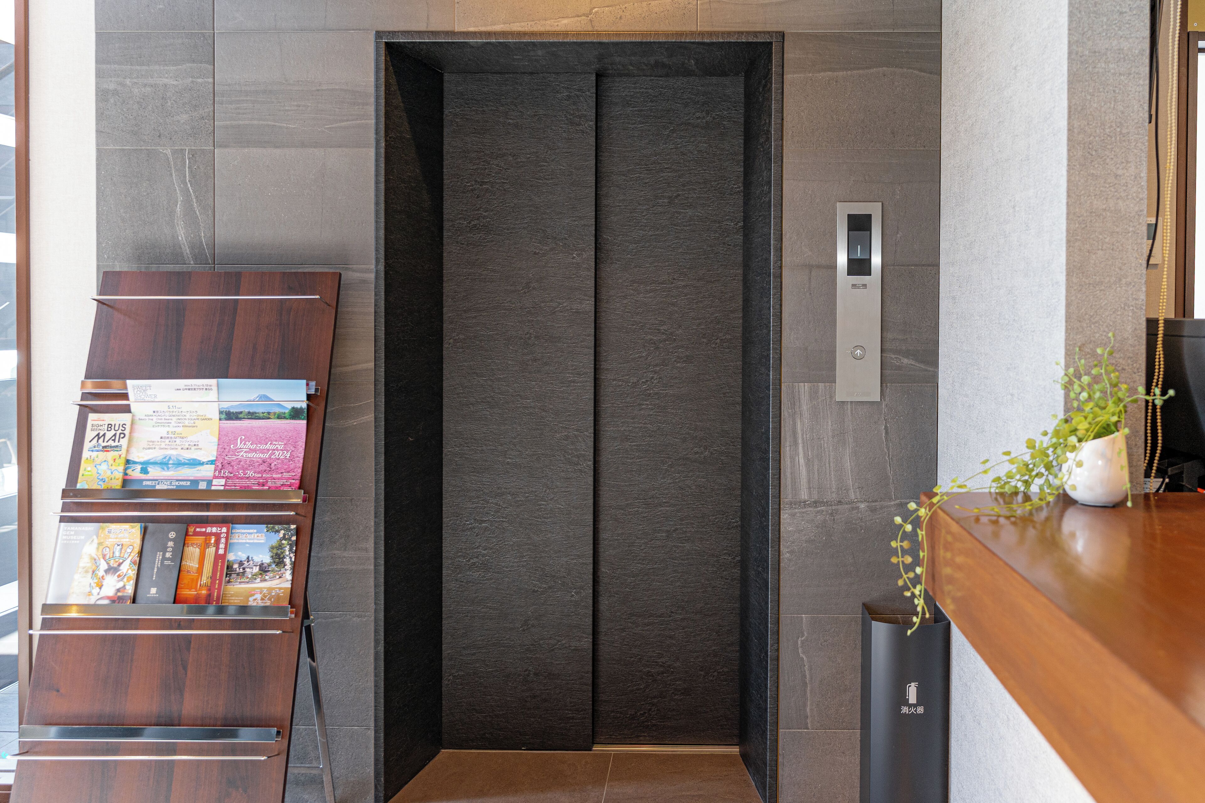 A modern elevator with a dark interior and a control panel on the wall.
