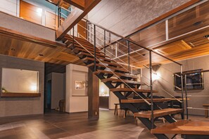 Un interior moderno con una escalera de madera, un comedor y vistas al exterior.