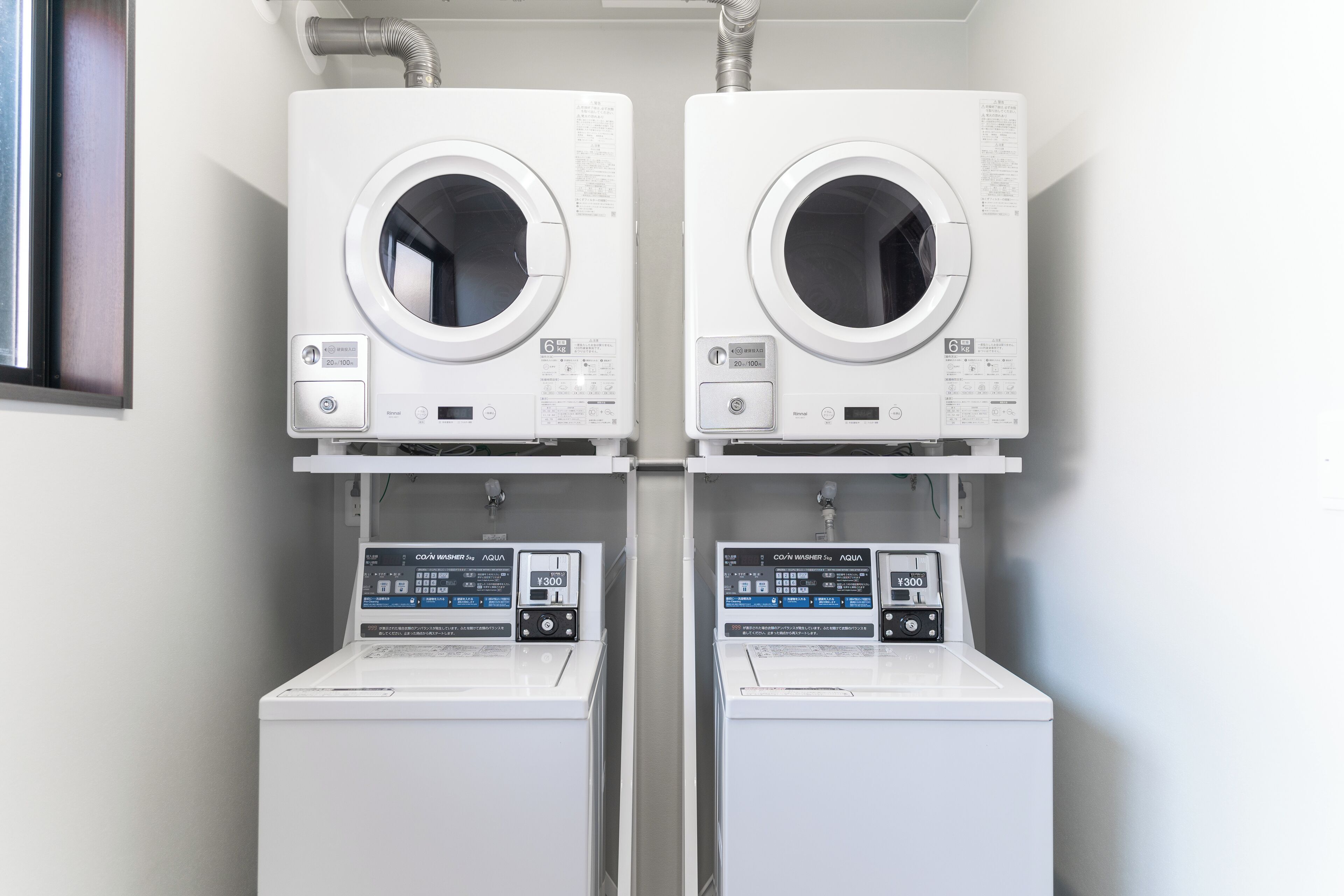 Two front-loading washing machines and dryers side by side in a laundry room.