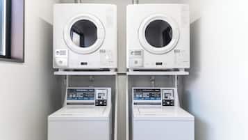 Two front-loading washing machines and dryers side by side in a laundry room.