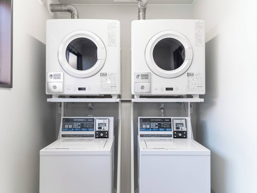 Two front-loading washing machines and dryers side by side in a laundry room.
