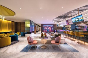 En modern entréhall med sittgrupper, en bar och en scen.