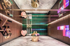 A modern interior with geometric wall designs, a central decorative table, and directional signage. - Manxin Hotel Jingzhong Yuci Longhu (Jinzhong)