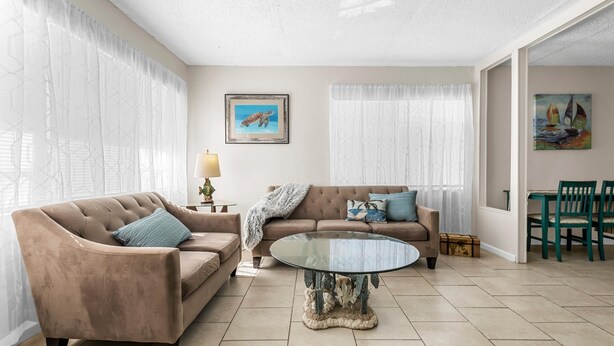 A living room with a beige sofa, a round glass coffee table, and a painting of a turtle on the wall.