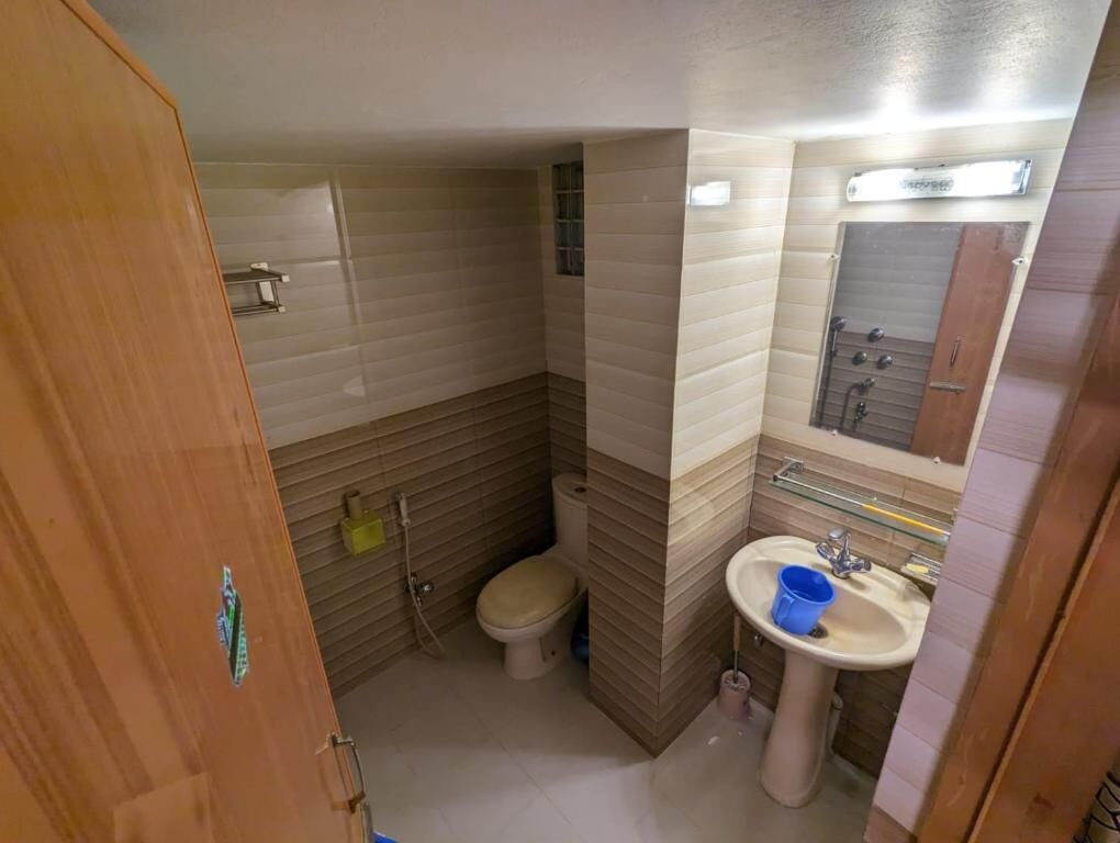 A compact bathroom with a toilet, sink, and mirror.