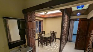 A room with a dining table, chairs, a ceiling fan, and a bathroom with a sink and mirror. - Rainagar rajbari (Sylhet)