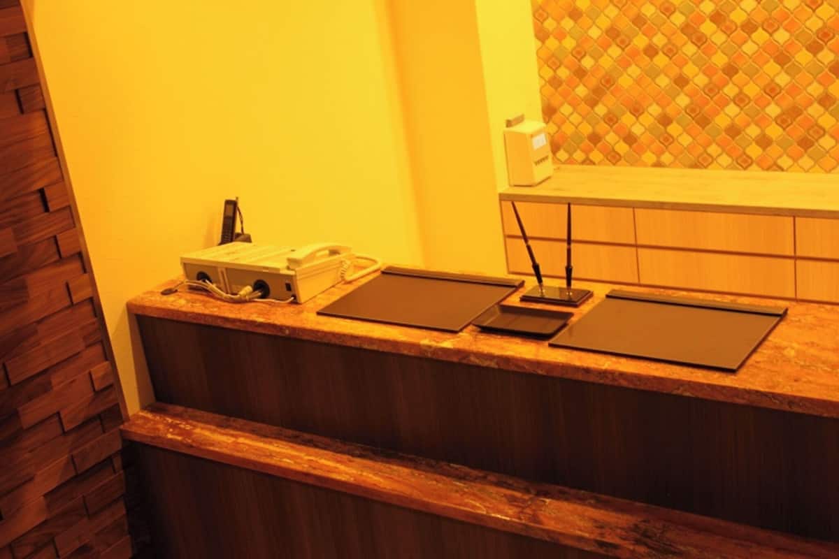 A reception desk with a telephone, a box, and a tablet.